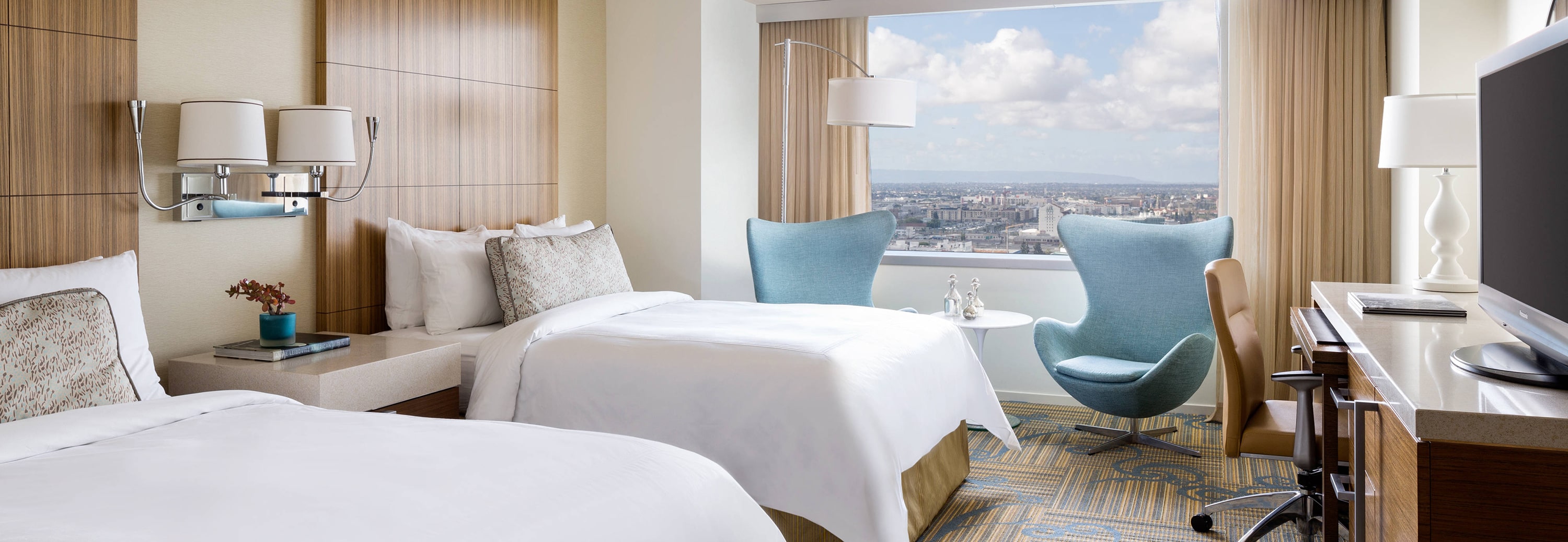 Clean hotel guestroom with white bedding and window treatments